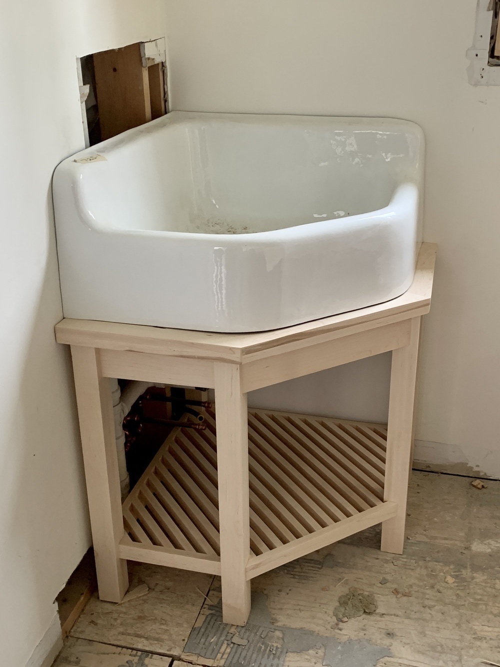large corner sink on a table with shelf below made of slats on diagonal