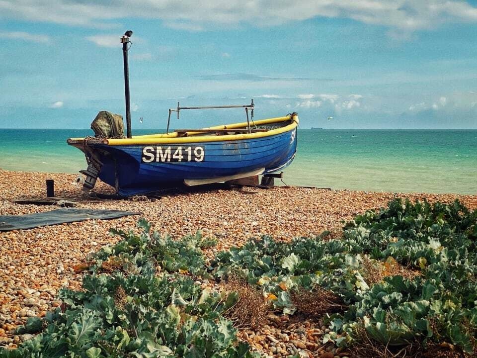 Small blue fishing boat on Worthing beach.