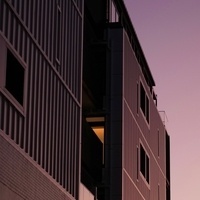 A dark grey building reflecting the violet wash of sunset