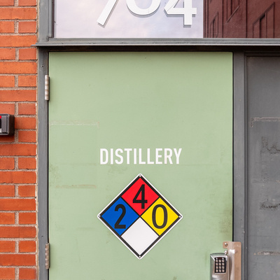 Photograph of a pale green door with the number 704 above it and an NFPA 704 hazard diamond sign reading \