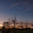 Auto-generated description: A serene sunset sky with silhouettes of leafless trees and minimal structures, set against an open park landscape.