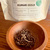 Auto-generated description: A wooden bowl filled with loose leaf tea is placed in front of a package labeled Kumari Gold from Kanchanjangha Tea Estate, Nepal.