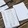 Handwritten note cards spread on a wooden table. There's a black pen beside them.