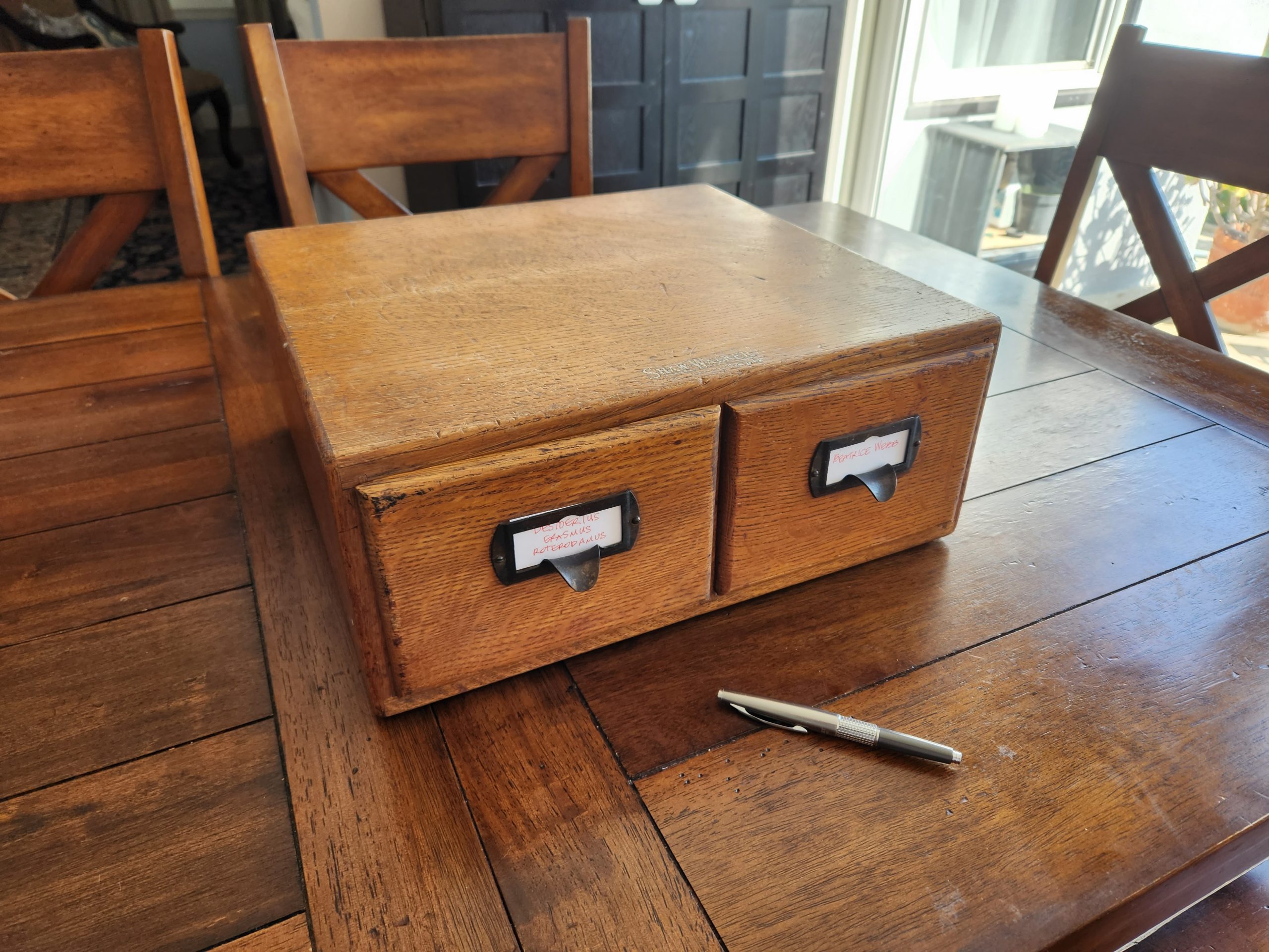 A two drawer wooden card index sitting on a wooden table