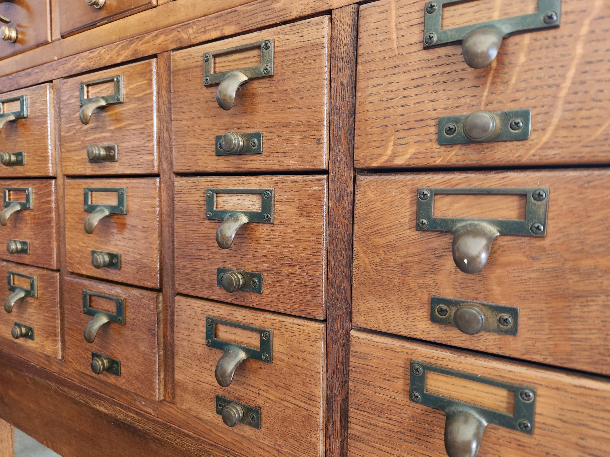 angle on a row of oak drawers with brass drawer pulls in a library card catalog