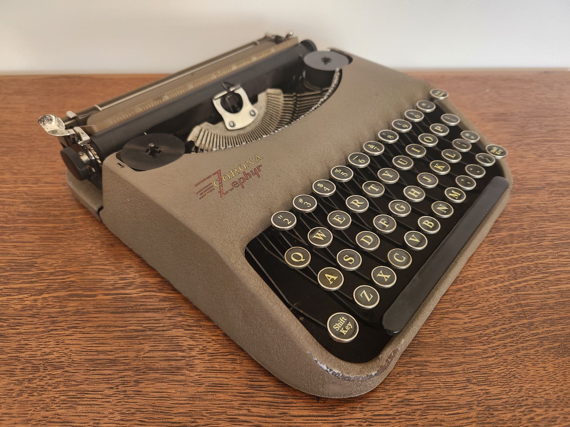 Oblique angle of a brown Corona Zephyr ultra-portable typewriter with black glass keys.