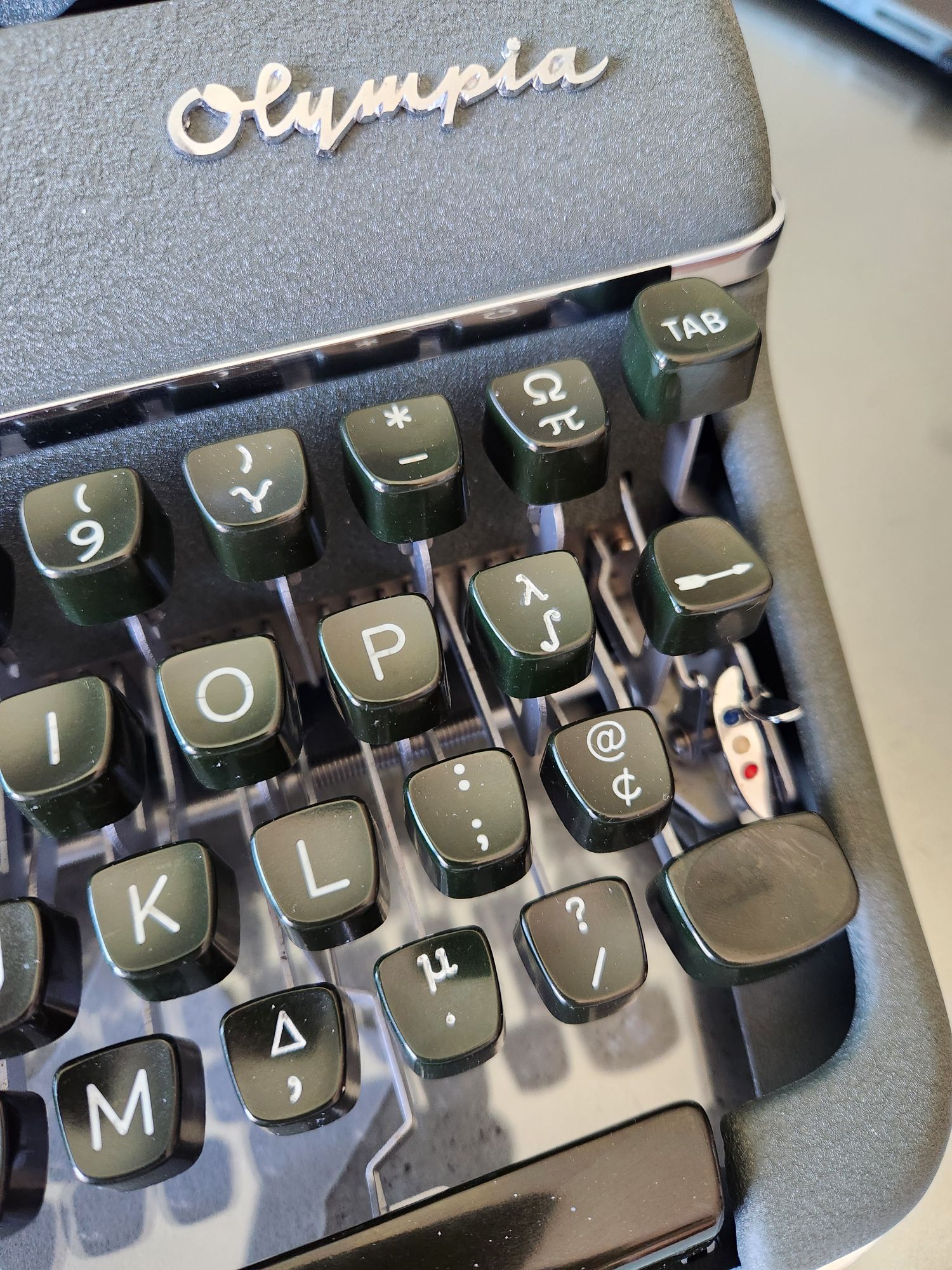 A close up view of the right side of a green 1958 Olympia SM3 typewriter that has some custom Greek and mathematical symbols