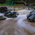 Muddy river cascading over a small weir into rocky rapids, long exposure blurring the water