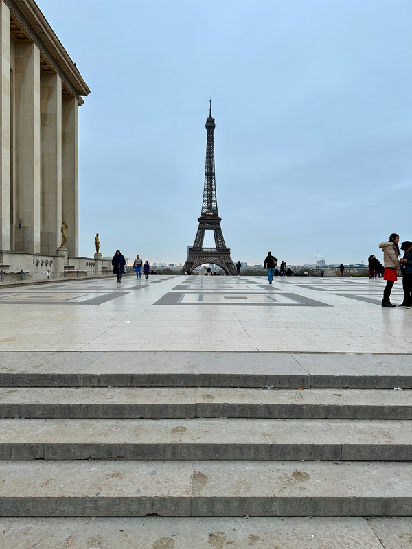Menschen spazieren auf dem Trocadéro-Platz mit Blick auf den Eiffelturm in Paris.