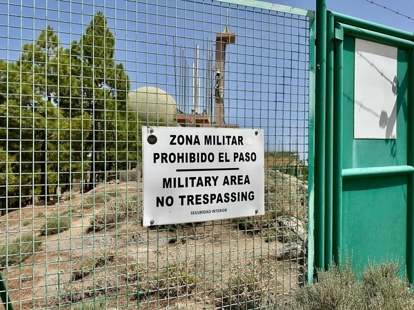 Ein Schild mit der Aufschrift Military Area - No Trespassing&quot; hängt an einem Metallzaun, der ein Gelände mit militärischen Einrichtungen auf dem Pico de las Nieves umgibt.