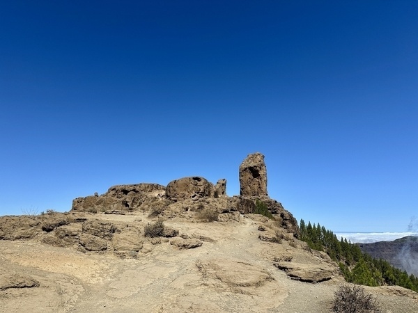 Ein Felsplateau mit dem markanten Roque Nublo unter klarem, blauem Himmel in der bergigen Landschaft von Gran Canaria.