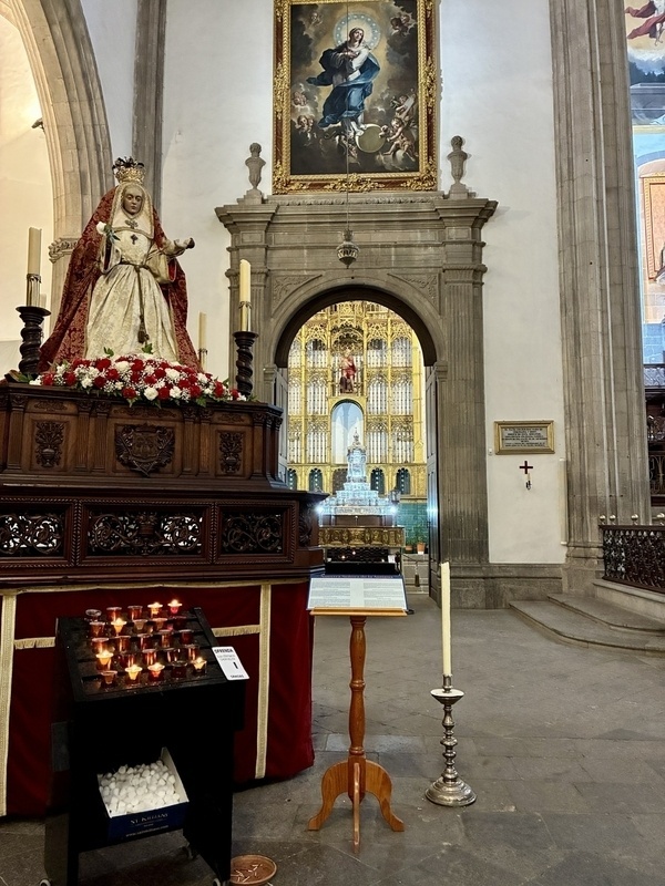 Eine reich verzierte Kirche mit einer religiösen Statue, Kerzenständern und einem imposanten Altar im Hintergrund.