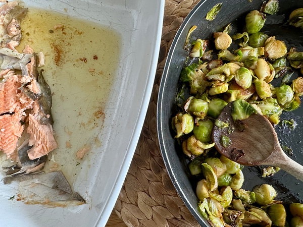 Eine Auflaufform mit Resten von Saibling und eine Pfanne mit gebratenem Rosenkohl sind zu sehen.