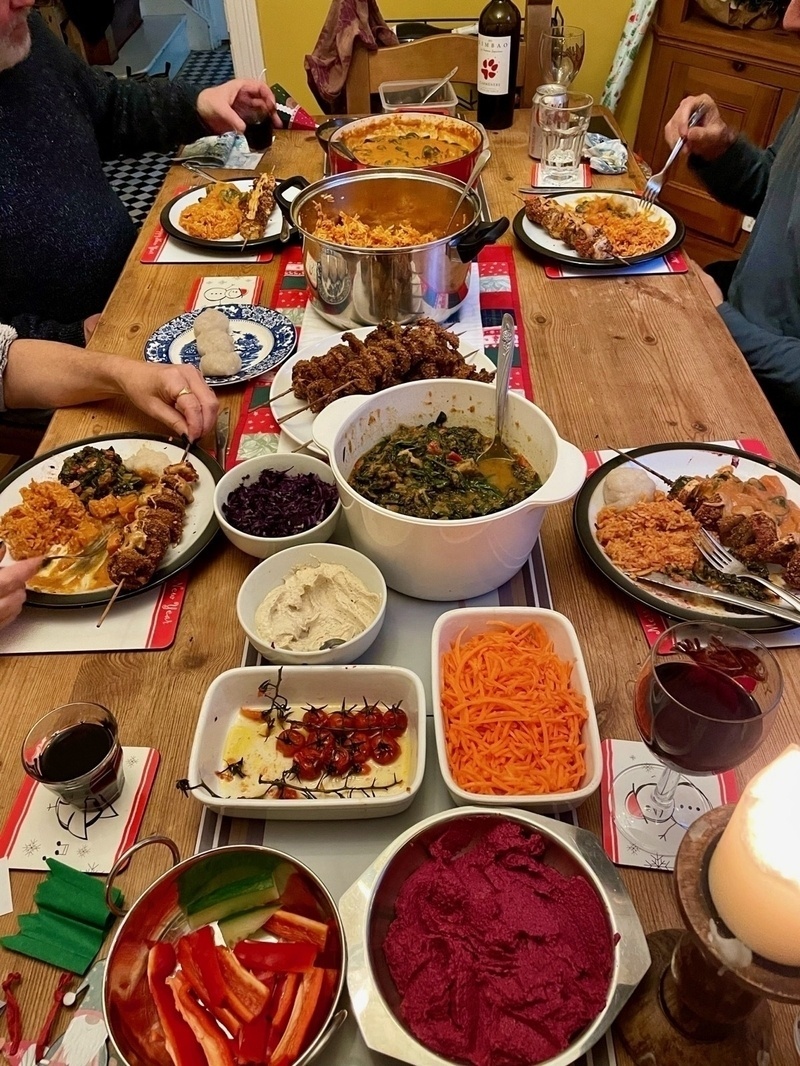 Dining table set for four filled with numerous plates and pots of food