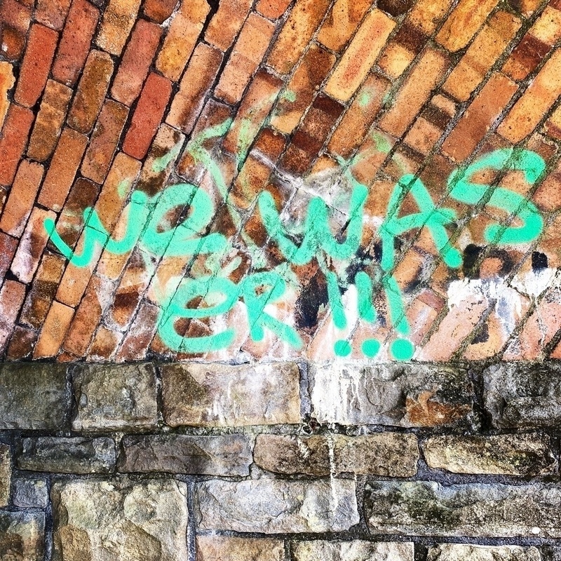 Graffiti on a brick wall reading we was er