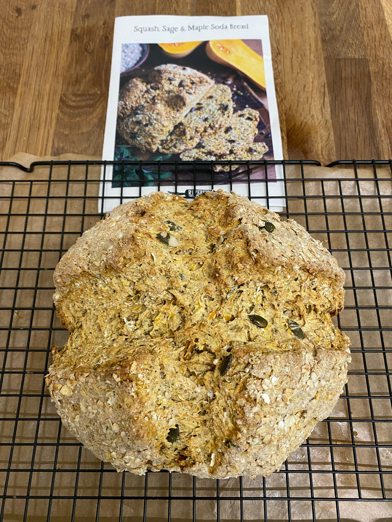 Round loaf of crusty, golden, baked bread on a cooling rack