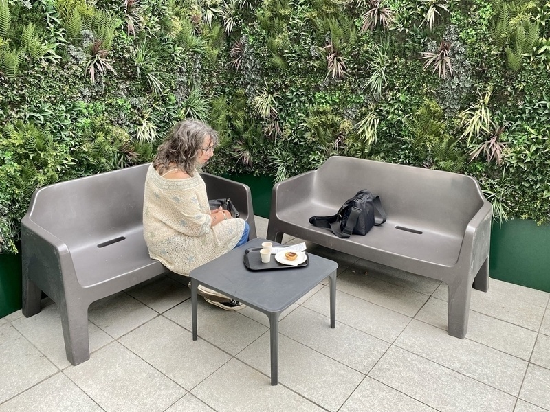 Woman sitting on a bench with nata and coffees on a table