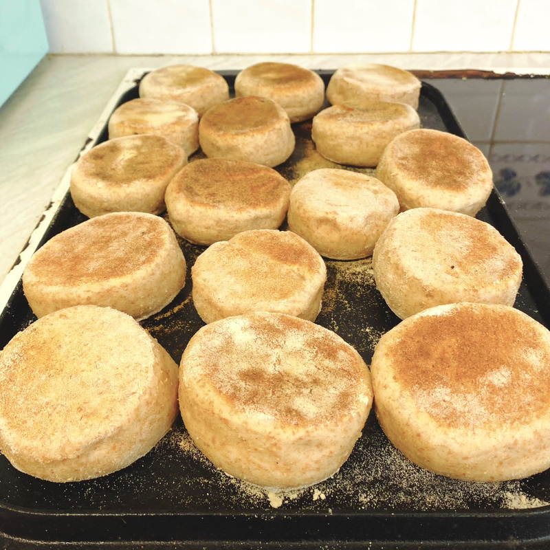Close up of browning muffins on a black cast iron griddle
