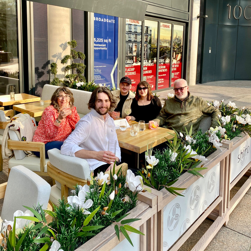 Five people sitting around table drinking cocktails