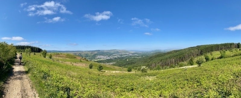 View over a town in avalley, woman standing on a path on the right of the picture