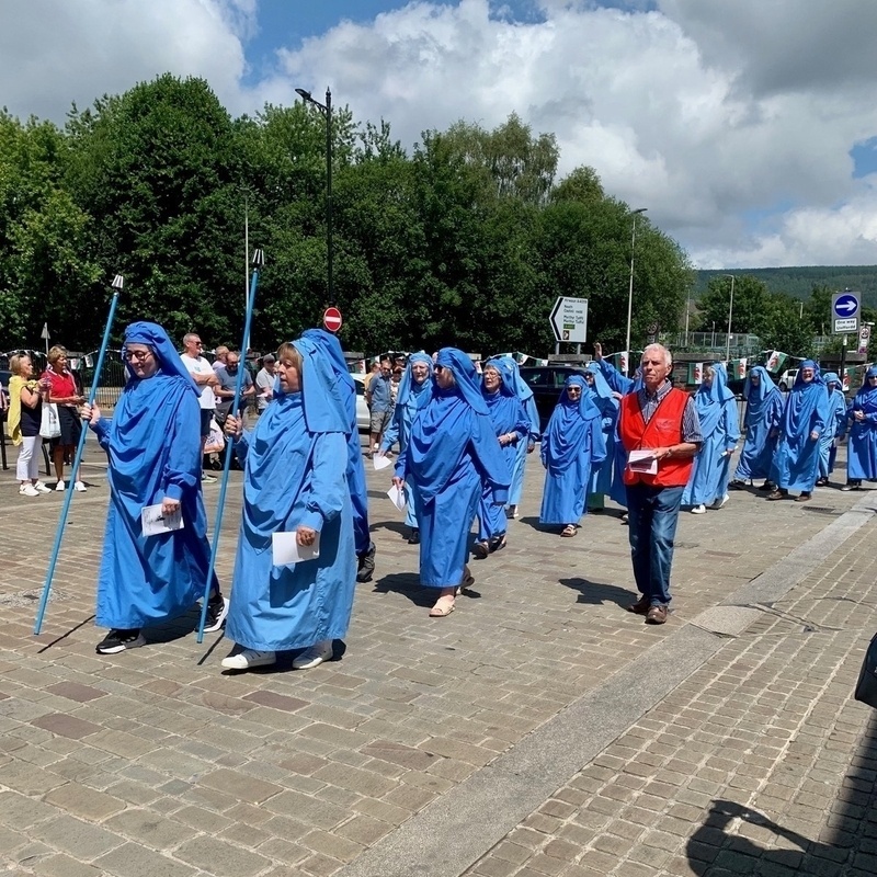 Procession of people in Druidic robes through a town centre