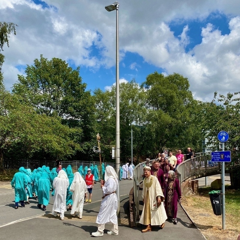 Procession of people in Druidic robes through a town centre