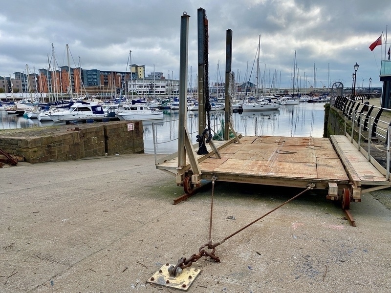 Concrete slipway leading into a marina full of masted boats