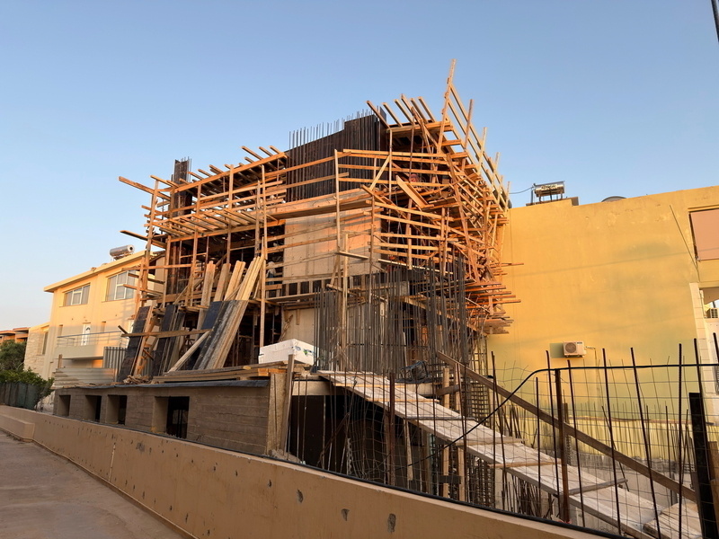 Auto-generated description: A building under construction is surrounded by wooden scaffolding and various construction materials.