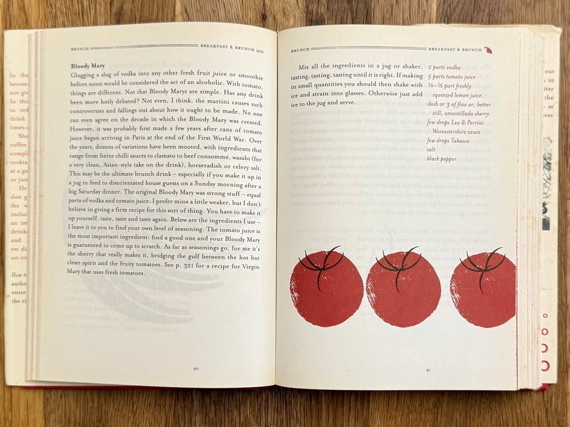 Auto-generated description: An open book displays a recipe for Bloody Mary on the left page and illustrations of three tomatoes on the right page.