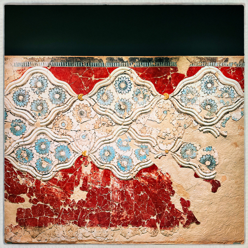 A vibrant mosaic features red and white cracked tiles with blue and white floral patterns arranged in ornate, diamond-shaped designs.