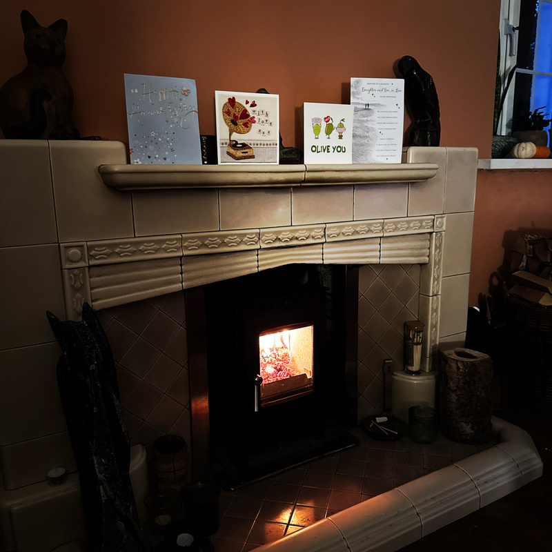Auto-generated description: A cozy fireplace is adorned with cards and decorations on the mantel, surrounded by a warm and inviting atmosphere.