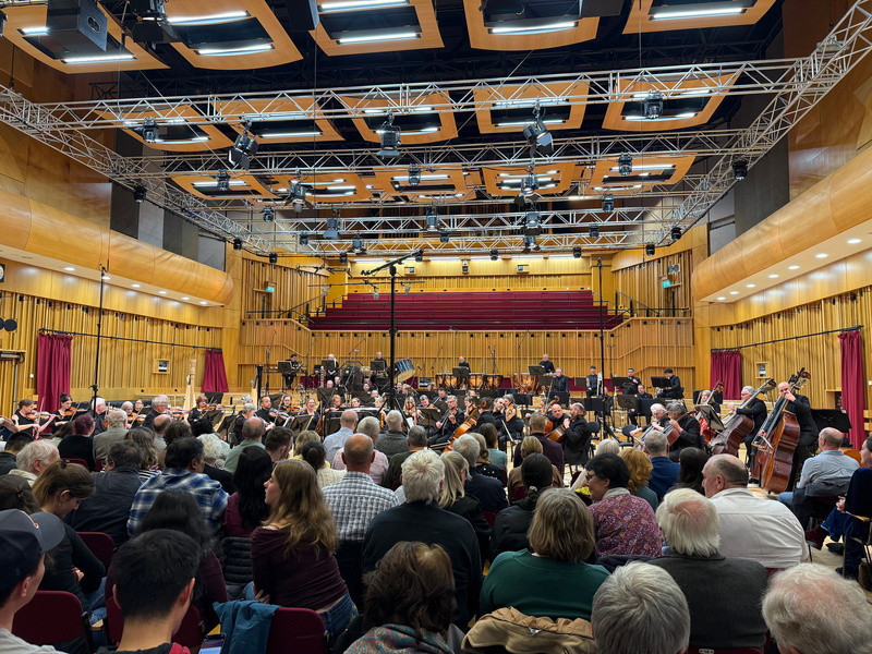 An orchestra is performing in a large concert hall filled with an audience.